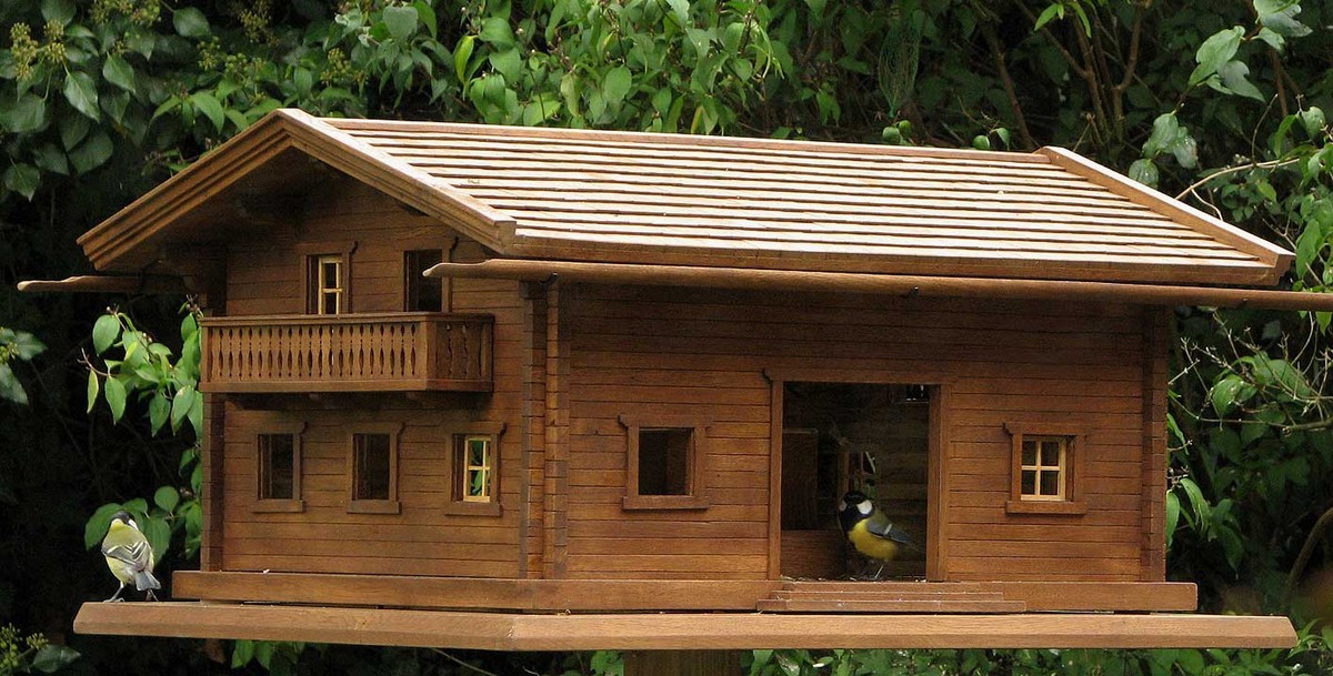 Lange Vogelvilla im alpinen Chalet-Stil mit Schindeldach und Meisen